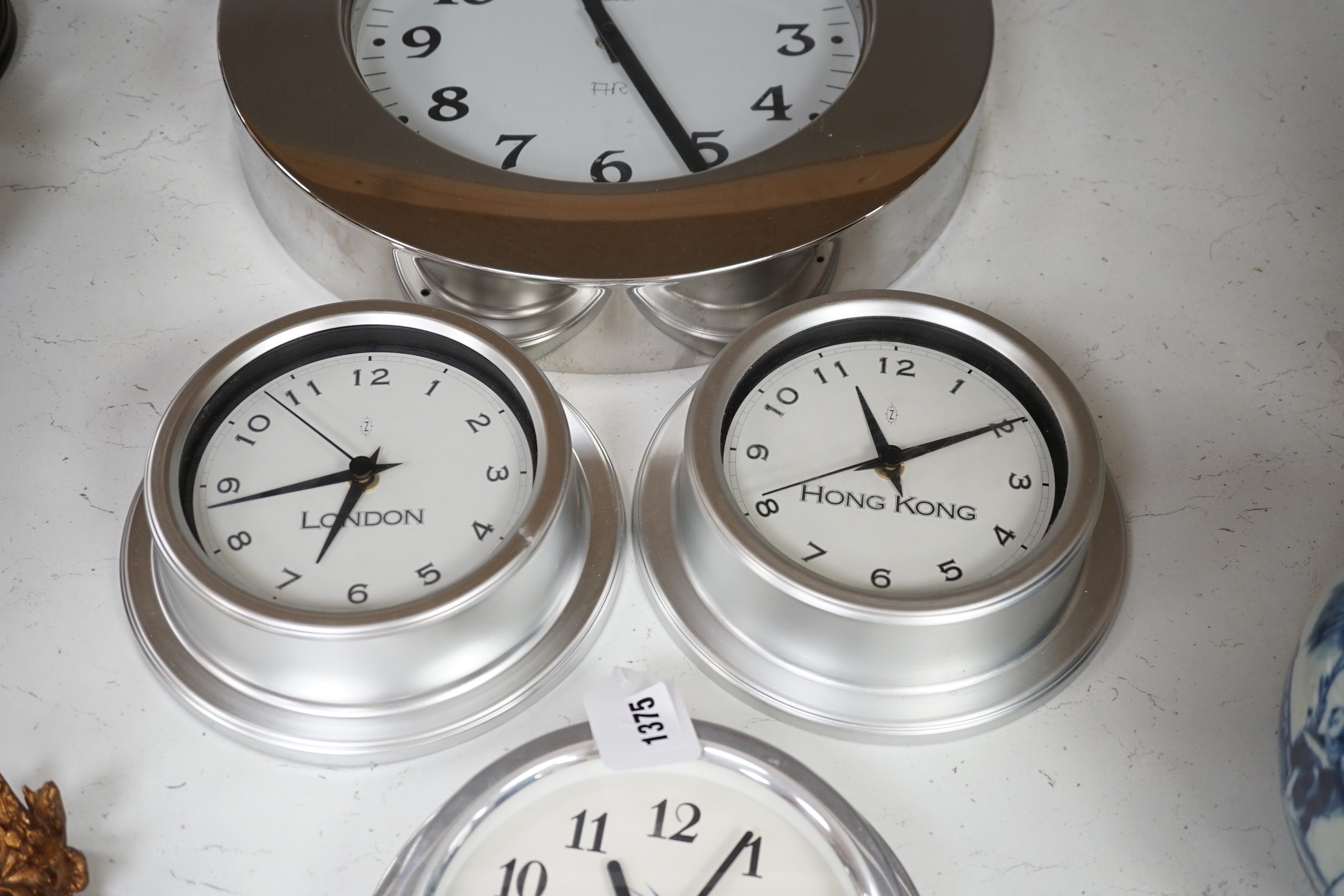 An Alessi wall clock and three similar smaller wall dials